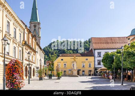 Farbenfrohe Geschäfte und Häuser am Stari Trg Platz mit der Kirche St. Daniel (Stolnica sv. Danijela), historisches Herz von Celje, Slowenien Stockfoto