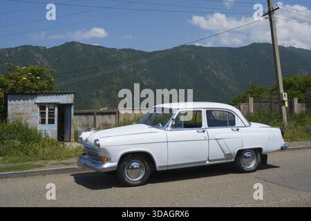 Weißer Oldtimer auf einer Landstraße mit Bergkulisse und blauem Himmel im Sommer, GAZ M-21 Volga, Odsun, Odzun, Debed Gorge, Provinz Lorikeet, Armen Stockfoto