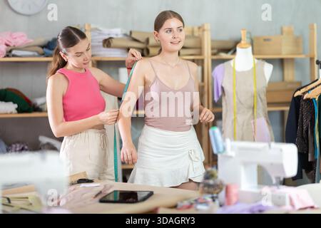 Erwachsene Näherin nimmt Körpermaße von jungen Frauen Stockfoto