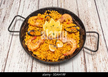Hummerpaella mit ganzen Muscheln als Beilage, serviert direkt von der Pfanne auf den Tisch. Stockfoto