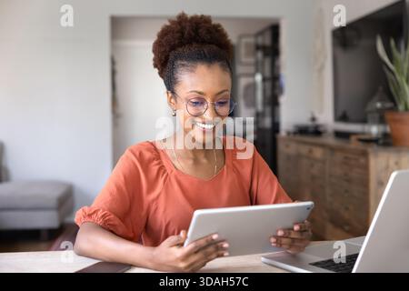 Positive junge afroamerikanische Berufsfrau, die von zu Hause aus arbeitet Stockfoto