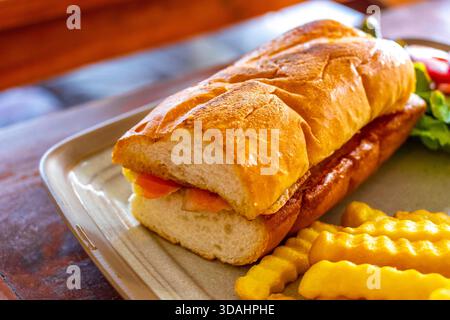 Lachs-Baguette-Sandwich mit Salat und Pommes frites auf einem Teller in einem Restaurant im Patong Beach Kathu District Phuket Island Provinz Südthailand Stockfoto