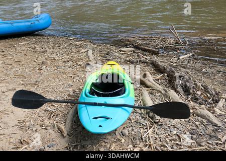 Farbenfrohes Kajak mit Paddeltour am Flussufer bereit für das Wassersportabenteuer im Sommer. Freizeitaktivitäten im Freien an einem friedlichen, ruhigen Tag für Spaß und explora Stockfoto