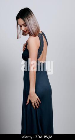 Junge Frau in Denim-Jeans und einem langärmeligen dunklen Oberteil, Seitenansicht Stockfoto