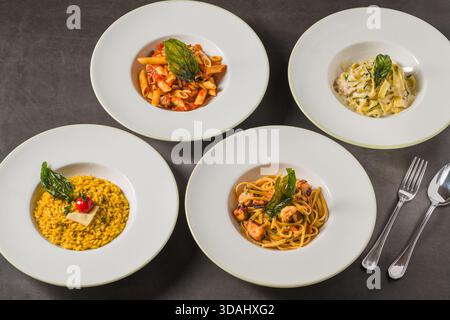 Verschiedene italienische Pasta- und Risottogerichte auf einem dunklen Tisch Stockfoto