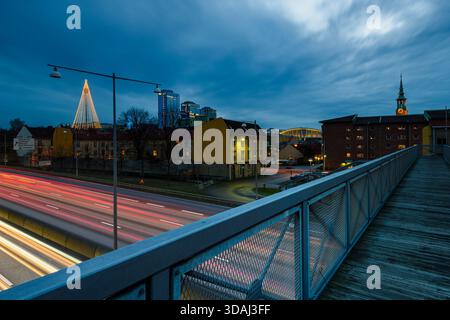 Abendlicher Blick auf Göteborg mit einer Autobahn mit leichten Wegen von Fahrzeugen. Nahe gelegene Gebäude sind zu sehen, zusammen mit Weihnachtsbeleuchtung und einer Kirche Stockfoto