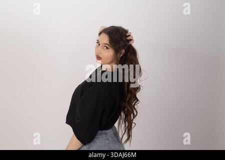 Junge Frau in schwarzem T-Shirt, lässiges Studio-Porträt, lächelnd Stockfoto