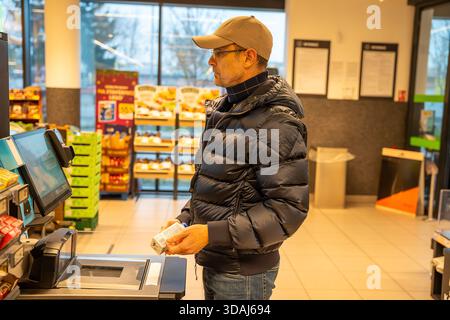 Mann, der einen Selbstkassenautomat in einem Supermarkt benutzt, der während einer Routine-Einkaufstour Artikel scannt. Konzept des modernen Einzelhandels, der Automatisierung und Stockfoto