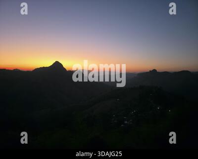 Wunderschöne und ruhige Silhouette der Berglandschaft in der Dämmerung. Farbenfroher Himmel bei Sonnenuntergang oder Sonnenaufgang sorgt für eine friedliche und ruhige Stimmung über dunkler Erbse Stockfoto
