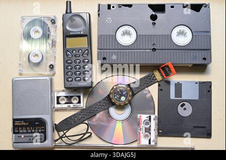 Nostalgisches Sortiment an Vintage-Technologie und Medienformaten aus den 1980er und 1990er Jahren einschließlich Mobiltelefon, VHS-Audio-Mikrokassetten Stockfoto