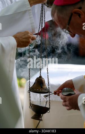 Heiligtum der Benite Fontaine. Ein Bischof gibt Weihrauch in einen Duftstoff, während während einer religiösen Zeremonie aromatischer Rauch aufsteigt. La Roche sur Foron. Fran Stockfoto