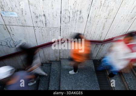 Lange Belichtung verwandelt Fußgänger in Lichtstreifen, diagonale Komposition betont die geschäftige Stadtbewegung. Stockfoto