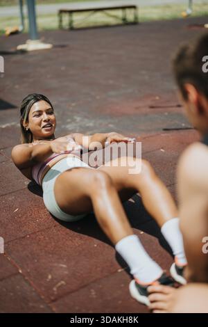 Indische Frau führt Bauchübungen auf Outdoor-Fitnessgeräten durch Stockfoto