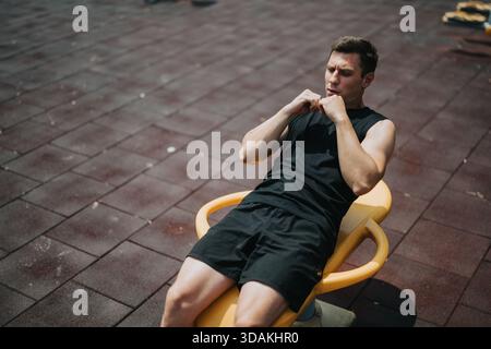 Ein Mann, der draußen auf einer Trainingsbank im Fitnessstudio Sit-UPS macht Stockfoto