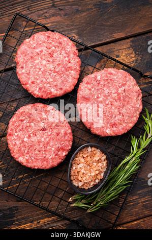 Rohe Fleischpasteten, Schnitzel, Hackfleisch für Burger. Hölzerner Hintergrund. Draufsicht Stockfoto