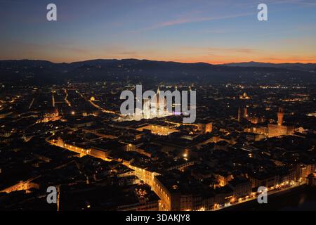 Blick aus der Vogelperspektive auf Florenz in der Abenddämmerung mit der beleuchteten Kathedrale von Florenz (Duomo di Firenze), die das historische Stadtzentrum in der Toskana, Italien, dominiert. Stockfoto