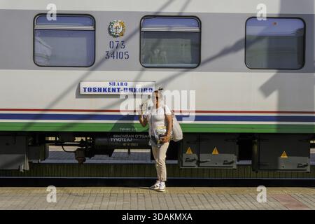 Lächelnder Tourist vor einem Zug in Buchara, Usbekistan Stockfoto