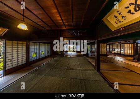 Der geräumige Hauptraum einer historischen Machiya in Nagiso, Nagano. Rechts hängt ein kakejiku (hängende Kalligraphie-Schriftrolle), links öffnen sich die Shoji-Türen zum Garten; die freiliegende Holzbalkenstruktur und die glatt polierten Holzrahmen sind typisch für den architektonischen Stil der reichen Kaufmannshäuser entlang des Nakasendo im 18. Und 19. Jahrhundert. Nagiso, Nagano, Japan Stockfoto
