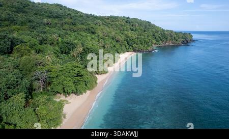 Atemberaubender Blick aus der Vogelperspektive auf einen unberührten Sandstrand, der auf das klare, lebhafte türkisfarbene und tiefblaue Meer trifft. Stockfoto