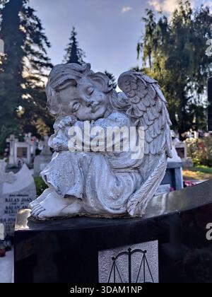 Eine Steinstatue eines schlafenden oder sitzenden Engels, wahrscheinlich ein Grabmarker oder ein Gartenschmuck auf einem Friedhof in Bistrita, Rumänien, 2020 Stockfoto