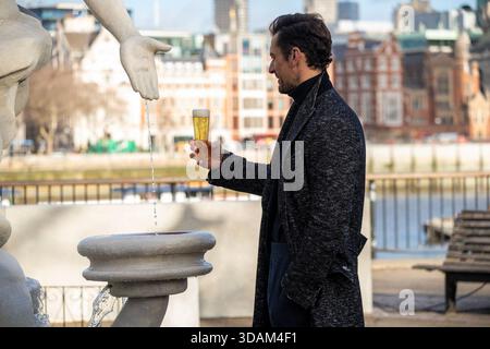 London, Großbritannien. Dezember 2025. Das englische Model David Gandy schaut sich sein Bier während der Dreharbeiten im Londoner South Bank an. Premium-Bier, Peroni Nastro Azzurro, Großbritanniens beliebtestes Bier, stellte am Aussichtspunkt in South Bank, London das La Fontana di Azzurro „Water into Beer“ des englischen Modells David Gandy vor. Der Anlass wird vom 10. Bis 14. Dezember 2025 für die Öffentlichkeit geöffnet sein, um die Feiertage in der Nation anzufeuern. Quelle: SOPA Images Limited/Alamy Live News Stockfoto