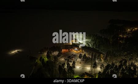 Blick aus der Vogelperspektive auf die beleuchtete Break Sokos Hotel Bomba eingebettet in die schneebedeckte Landschaft, Kontiolahti, Nordkarelien, Finnland. Stockfoto