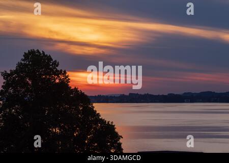 Sonnenuntergang über dem Bodensee mit ruhigem Wasser und Wolken, die das Abendlicht reflektieren, Mitteleuropa Stockfoto