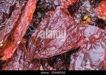 Getrocknete rote Paprika sind zusammen angeordnet und zeigen ihre satte Farbe und einzigartige Textur. Diese Szene findet auf einem lokalen Markt statt, wo verschiedene Arten von p Stockfoto