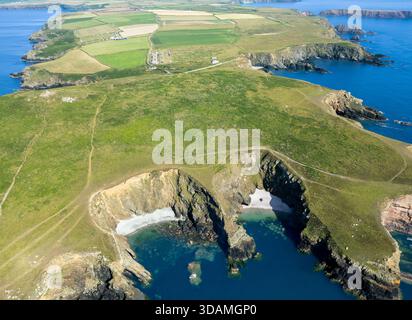 Blick aus der Vogelperspektive auf zerklüftete Klippen, die versteckte Buchten umgeben, wo das türkisfarbene Meer auf das grüne Land trifft, West Hook, Pembrokeshire, Wales. Stockfoto