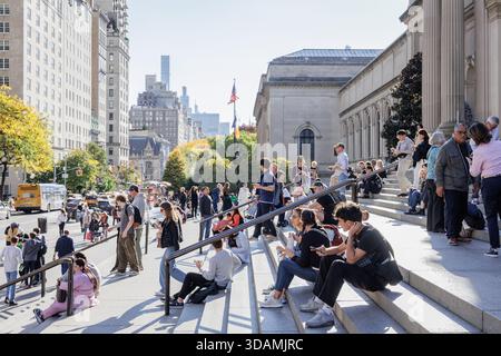 Die Menschenmassen entspannen sich und machen Selfies auf den Stufen des Metropolitan Museum of Art Stockfoto