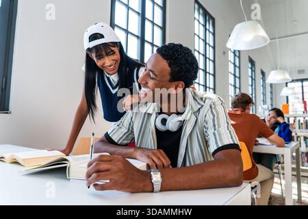 Multiethnische Gruppe junger Studenten, die sich in der Bibliothek treffen - junge multiethnische Universitätsfreunde, die eine Pause vom Studium genießen, an einem P Stockfoto