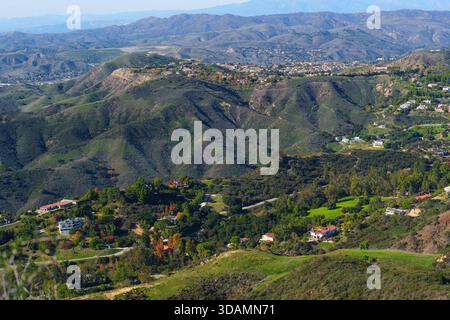 Die erhöhte Perspektive erfasst weitläufige Wohnsiedlungen, die sich in einem grünen, zerklüfteten Gelände der Santa Monica Mountains unter einem klaren blau verschmelzen Stockfoto