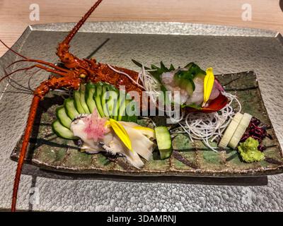 ISE-Hummer (Ise-EBI) diente als Sashimi, aufwendig auf einem rechteckigen Teller angeordnet: Der ganze Hummer ruht auf fein geschnittenen Gurken, begleitet von rohem Hummer in Muschelschale, Wakame Algen, Daikon-Rettich und Wasabi. Eine Spezialität der Küche von Toba, Präfektur Mie, Japan Stockfoto