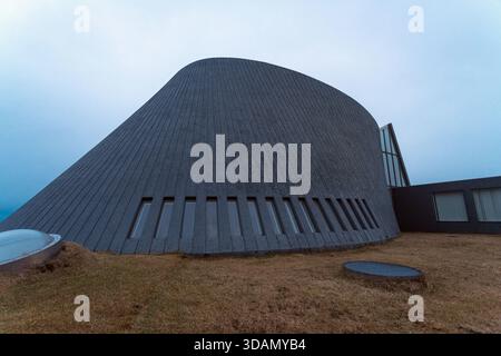 Der Blick auf die markante, dunkle, moderne Kirche erhebt sich vor einem gedämpften Himmel, ein architektonisches Wunder der isländischen Landschaft, Blonduoskirkja, Blonduos, Eis Stockfoto