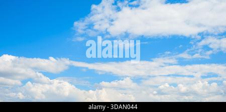 Ein klarer und hellblauer Himmel ist mit weichen, flauschigen Wolken gefüllt, die tagsüber eine friedliche Atmosphäre schaffen. Stockfoto