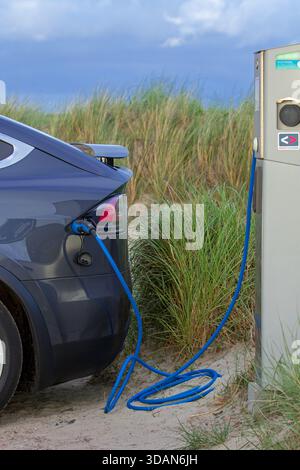 Elektrofahrzeug / EV-Ladung an öffentlicher Ladestation / Ladestation für Elektroautos in den Dünen auf der Insel Texel, Niederlande Stockfoto