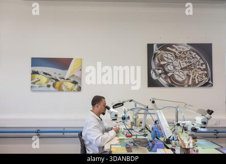 Ein Uhrmacher der Lederer Manufaktur in St-Blaise, Schweiz, inspiziert ein fein veredeltes Bauteil mit einem Hochleistungsmikroskop. Stockfoto