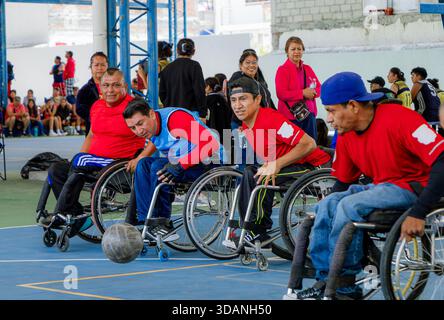 Männliche Spieler in Hochleistungs-Rollstühlen treten in einem angepassten Basketballspiel an, während die Zuschauer im Hintergrund zusehen. Stockfoto