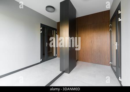 Innenraum eines modernen Wohngebäudes. Stilvolle Lobby mit schwarzer Mittelsäule und eingebauten Metallbriefkästen. Das Feld enthält g Stockfoto