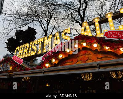 Manchester, Großbritannien - 16. November 2025: Ein lebhafter Weihnachtsmarkt in Manchester, der mit warmen Lichtern, Girlanden und saisonalen Schildern erstrahlt. Stockfoto