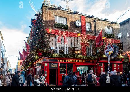 Der historische Temple Bar Pub in Dublin, Irland, ist hell mit üppigen Weihnachtsbäumen, Lichtern und roten Schleifen an der Fassade dekoriert. Stockfoto