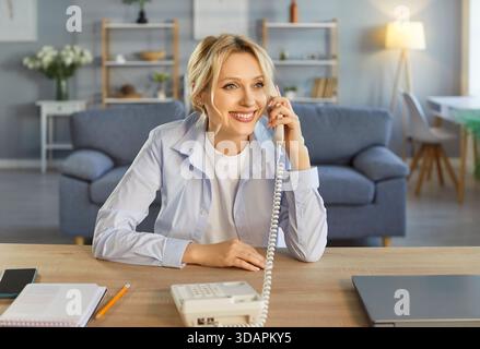 Geschäftsfrau, die am Arbeitsplatz in lässiger Kleidung sitzt und telefoniert. Stockfoto