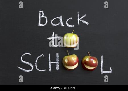 Zurück zur Schule Phrase mit lächelnden Äpfeln, die auf der Tafel handgeschrieben sind Stockfoto