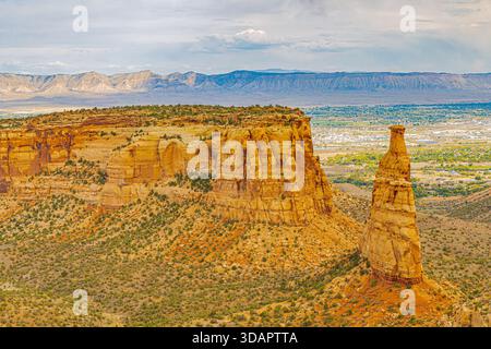 Eine atemberaubende Aussicht, die den beeindruckenden Kontrast zwischen einer massiven, flachen Sandstein-mesa und dem Independence Monument am Colorado National Monument einfängt Stockfoto
