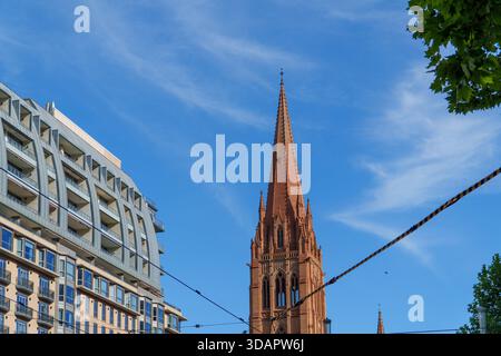 Der markante rote Backsteinturm der St. Pauls Cathedral erhebt sich vor einem klaren blauen Himmel, flankiert von einem modernen Wohngebäude und durchquert Sie Stockfoto