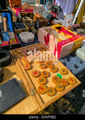 IPOH, MALAYSIA – 9. NOVEMBER 2025: Chinesische Schachfiguren aus Holz (Xiangqi) werden auf einem Klappbrett angeordnet, das an einem Marktstand zum Verkauf angeboten wird. Stockfoto