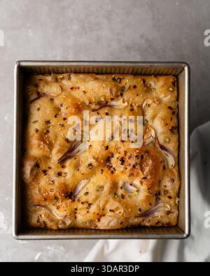 Draufsicht von Zwiebeln- und Schalottenfokaccia, Draufsicht von luftig sprudelnden Zwiebelfokaccia auf einer Zementplatte Stockfoto