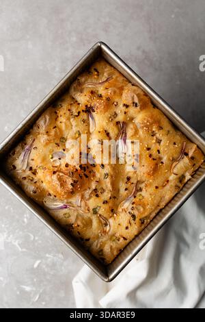 Draufsicht von Zwiebeln- und Schalottenfokaccia, Draufsicht von luftig sprudelnden Zwiebelfokaccia auf einer Zementplatte Stockfoto
