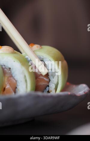 Sushi-Brötchen, serviert auf einem Teller mit Essstäbchen Stockfoto