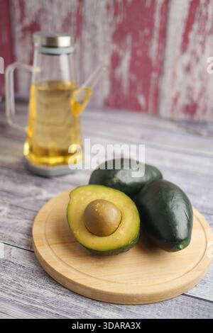 Frische Avocados auf einem Holzbrett mit Öl im Hintergrund Stockfoto